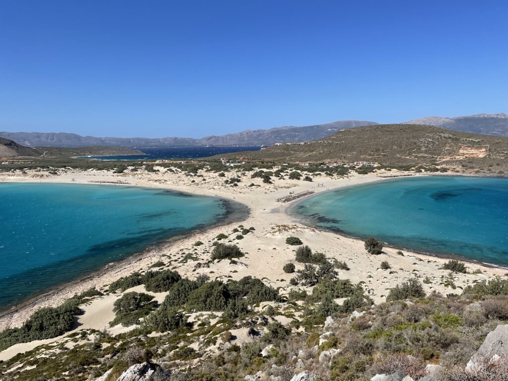 Per fotografare la spiaggia di Simos, salite sul promontorio che si trova alla fine della lingua di sabbia che la divide in due parti
